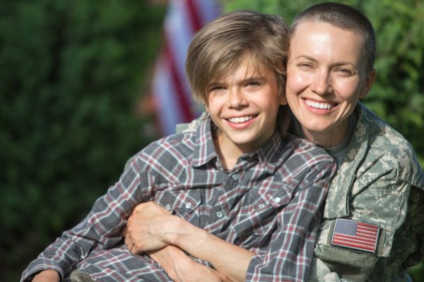 Happy,Reunion,Of,Female,Mother,Soldier,With,Family,Son,Outdoors