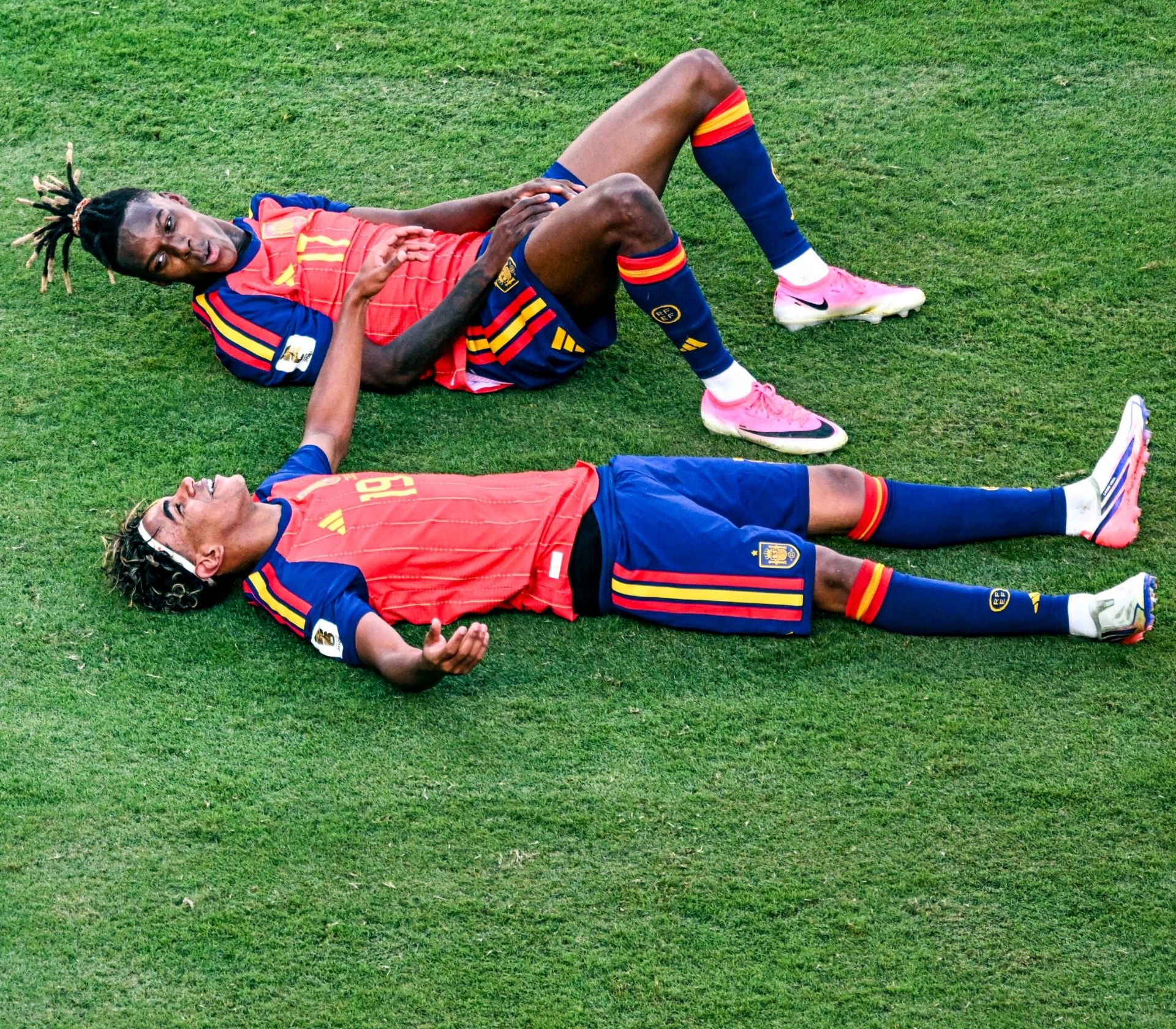 Nico Williams and Lamine Yamal lie together on the pitch after the World Cup final, sharing a moment of exhaustion, relief, and celebration.