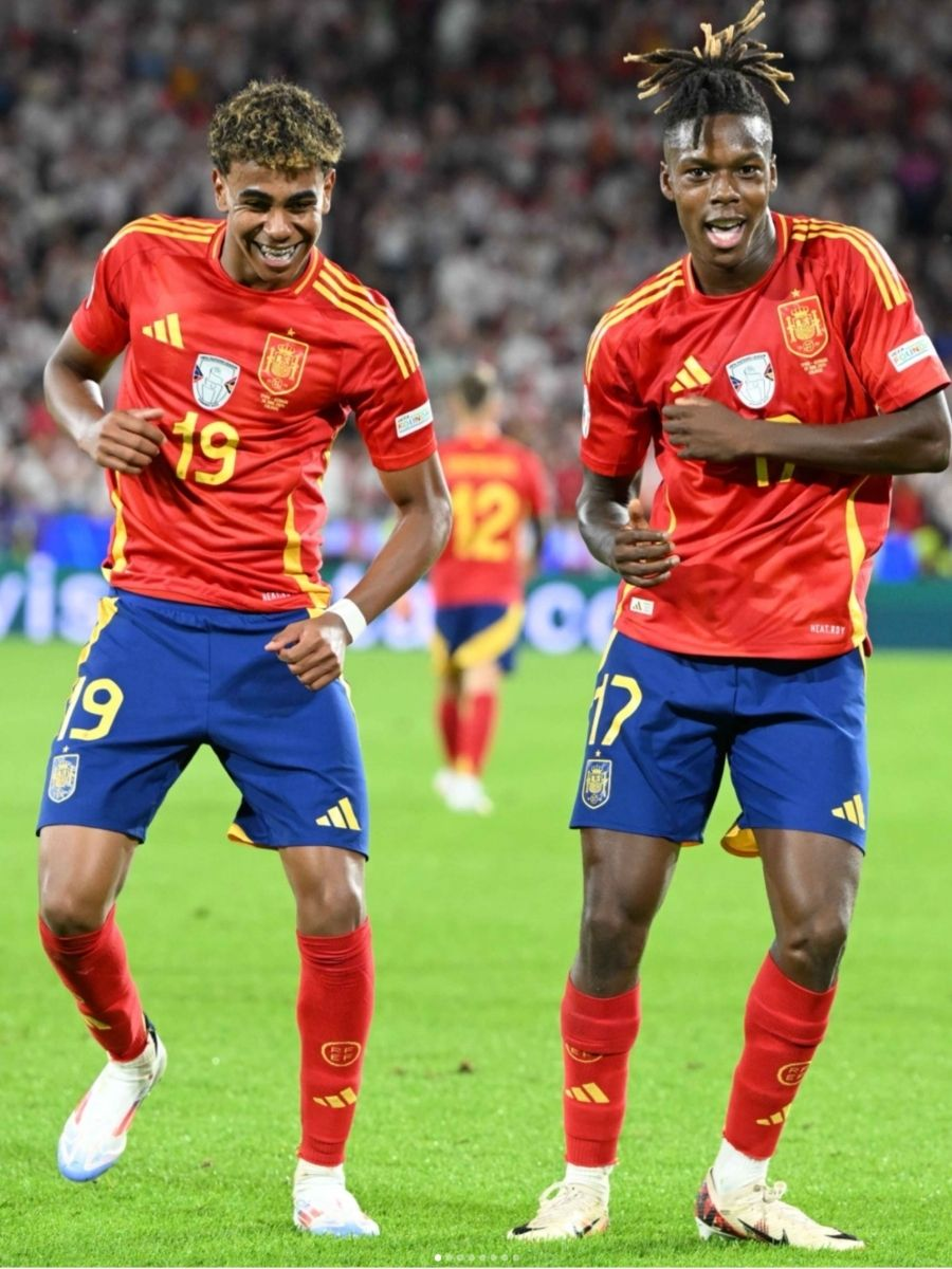 Lamine Yamal and Nico Williams celebrate together in Spain uniforms on the pitch, representing the youthful energy and bright future of football.